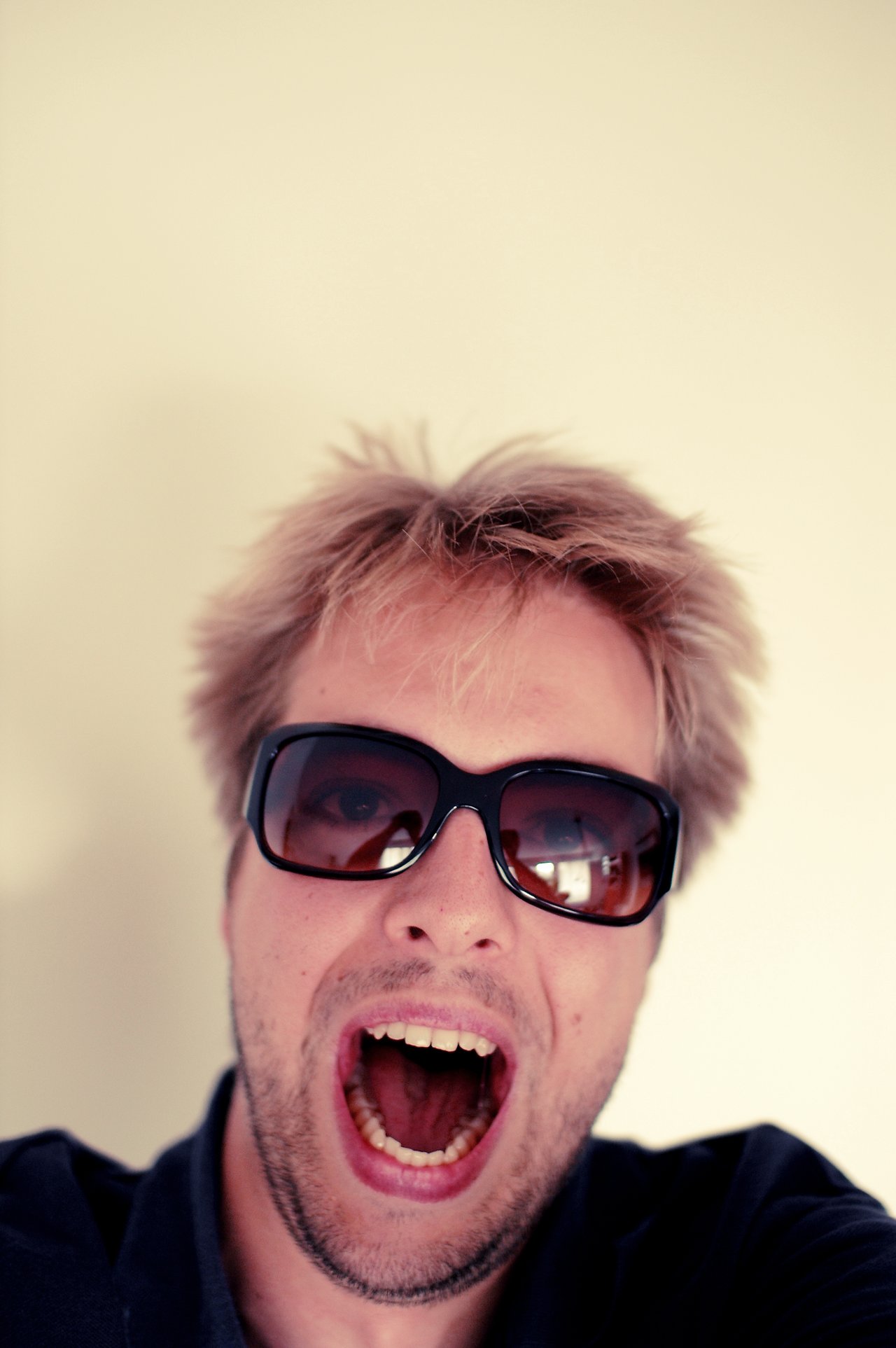 Tah dries A person with sunglasses and messy hair opens their mouth wide, possibly shouting or reacting excitedly.